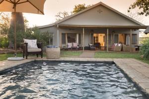a swimming pool in front of a house with an umbrella at Baobab Hill House in Makuleke Contract Park +25 photos