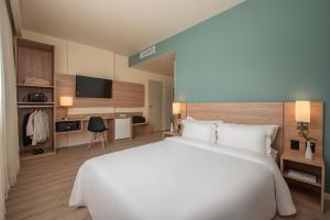 un grande letto bianco in una camera d'albergo di Intercity Curitiba Batel a Curitiba