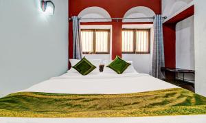 een slaapkamer met een groot wit bed met groene kussens bij Ganga Fuji Home in Varanasi