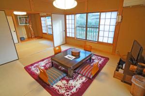 a living room with a table and a rug at Yufunoyado Kifu in Yufu