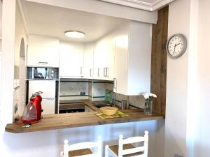 a kitchen with white cabinets and a clock on the wall at Aldeas De Aguamarina Cabo Roig in Orihuela Costa