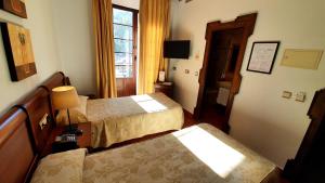 アンテケラにあるコソ ビエホのベッド2台と窓が備わるホテルルームです。