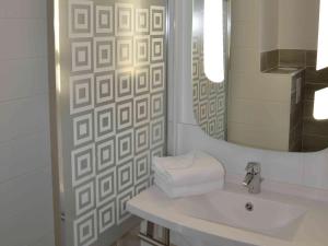 Baño blanco con lavabo y espejo en ibis Europe Chalon Sur Saone, en Chalon-sur-Saône