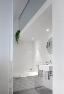 Baño blanco con bañera y lavamanos en Alphabed & Bike, en Gante