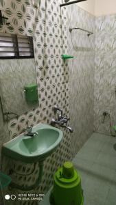 uma casa de banho com um lavatório verde e um espelho em Barnabas Homestay em Thanjavur