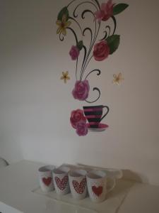 a row of coffee cups on a shelf with a vase at Sweet Dreams Apartment in Varaždin