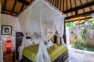 a bedroom with a bed with a canopy at Lodtunduh Sari in Ubud