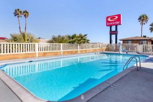 uma piscina com uma placa de hotel e palmeiras em Econo Lodge On Historic Route 66 em Barstow