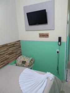 Habitación con cama y TV en la pared. en POUSADA DOS AMIGOS en Presidente Venceslau