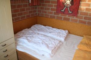an unmade bed in a room with a brick wall at Rekerlanden 97 in Schoorldam