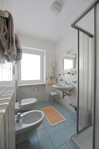 a white bathroom with two sinks and a shower at Hotel Fiorenza in Campitello di Fassa
