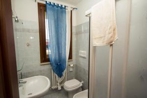 a bathroom with a toilet sink and a blue shower curtain at B&B La Dimora delle Calendule in Virgilio