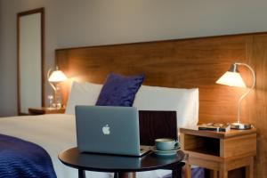 a bed with a laptop on a table in a hotel room at Osprey Hotel in Naas