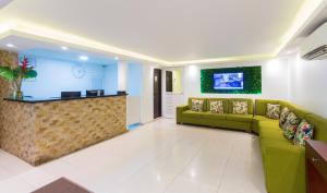 a waiting room with green couches and a bar at Hotel Avexi Suites By GEH Suites in Cartagena de Indias