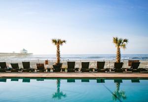 富丽海滩Tides Folly Beach, Charleston's Oceanfront Hotel的海滩旁的游泳池设有椅子和棕榈树