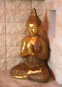 een gouden standbeeld van een Boeddha zittend op de vloer bij Luxury Suite in Rimini