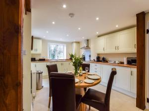 a kitchen with a wooden table with chairs and a dining room at Queen Mary in Winchcombe