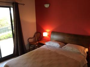 um quarto com uma cama com uma parede vermelha e uma janela em Casa do Nuno T1 em Horta