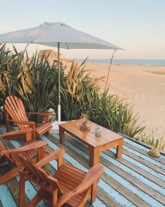 una mesa, sillas y una sombrilla en la playa en Remanso del Diablo, en Punta del Diablo