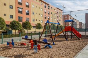 a playground in the sand in front of a building at Descanso-elegancia en Sevilla Parking Gratuito in Seville
