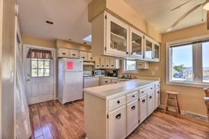 a kitchen with white cabinets and a white refrigerator at East of the Sun Beachside Apartment with Deck! in Emerald Isle
