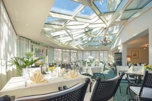 ein Restaurant mit weißen Tischen und Stühlen und einer Glasdecke in der Unterkunft Hotel Andreas in Dresden