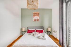 Schlafzimmer mit einem weißen Bett und roten Kissen in der Unterkunft Le First by Cocoonr in Nantes
