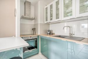eine Küche mit blauen Schränken und einem Waschbecken in der Unterkunft Le First by Cocoonr in Nantes