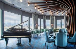 a room with a piano and chairs and windows at Hotel Adamo in Tbilisi City