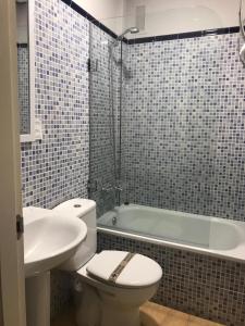 a bathroom with a toilet and a sink and a tub at Hostal Goyesco Plaza in Plasencia