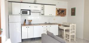 a kitchen with white cabinets and a table with a couch at Vistas para el relax in Puntallana