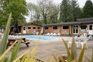 a resort with a pool and chairs and a building at Bluebell Lodge set in a Beautiful 24 acre Woodland Holiday Park in Newcastle Emlyn