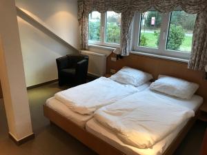 uma cama num quarto com uma cadeira e janelas em Pension Heimliche Liebe em Essen