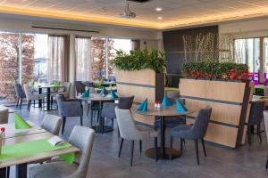 a restaurant with tables and chairs and plants at Mezzo Beringen in Beringen