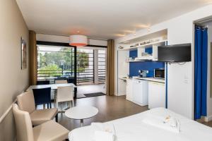een keuken en een woonkamer met een tafel en stoelen bij SOWELL Family Riviera in Saint-Raphaël