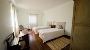 um quarto branco com 2 camas e uma janela em Quinta dos Lameiros em Vila Nova de Poiares