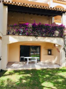 un banco blanco al lado de un edificio con flores púrpuras en Apartamentos El Toro, en Marbella