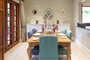 a dining room with a wooden table and blue chairs at Oyster Cottage in Durban +5 photos