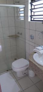 La salle de bains blanche est pourvue de toilettes et d'un lavabo. dans l'établissement Tureck Garten Hotel, à Corupá