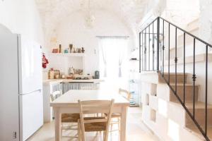 biała kuchnia ze stołem i schodami w obiekcie Le Terrazze Ferrigni w mieście Ostuni