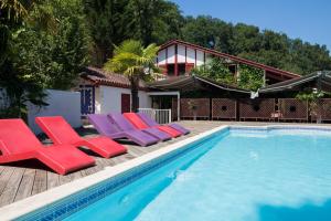 - une piscine bordée de chaises longues rouges et violettes dans l'établissement Les Collines Iduki, à Labastide-Clairence