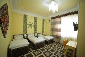a room with three beds and a table and a window at Fayz Guest House in Khiva