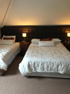 キラローにあるLakeland House B&Bのベッド2台、テーブル上のランプ2つが備わるベッドルーム1室