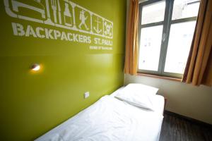 a bedroom with a bed with a green wall and a window at Backpackers St. Pauli in Hamburg