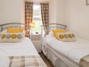 two twin beds in a room with a window at Dalesway Cottage in Windermere