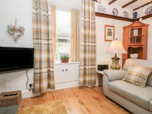 a living room with a couch and a tv at Dalesway Cottage in Windermere