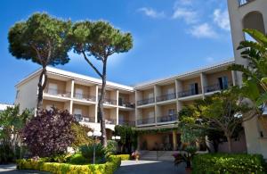 duży apartamentowiec z drzewami i krzakami w obiekcie Hotel Terme Alexander w mieście Ischia