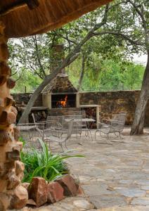 Un patio con chimenea, sillas y fogata. en Bridgewaters Horse Park Tranquil Country Cottage, en Hekpoort
