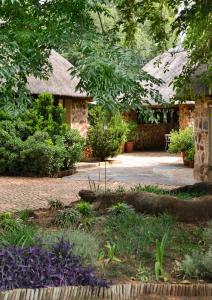 Un jardín con una casa de piedra con un camino. en Bridgewaters Horse Park Tranquil Country Cottage, en Hekpoort 2 fotos más
