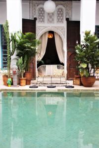 - une piscine avec une chaise et des plantes dans l'établissement Riad El Ouarda, à Marrakech